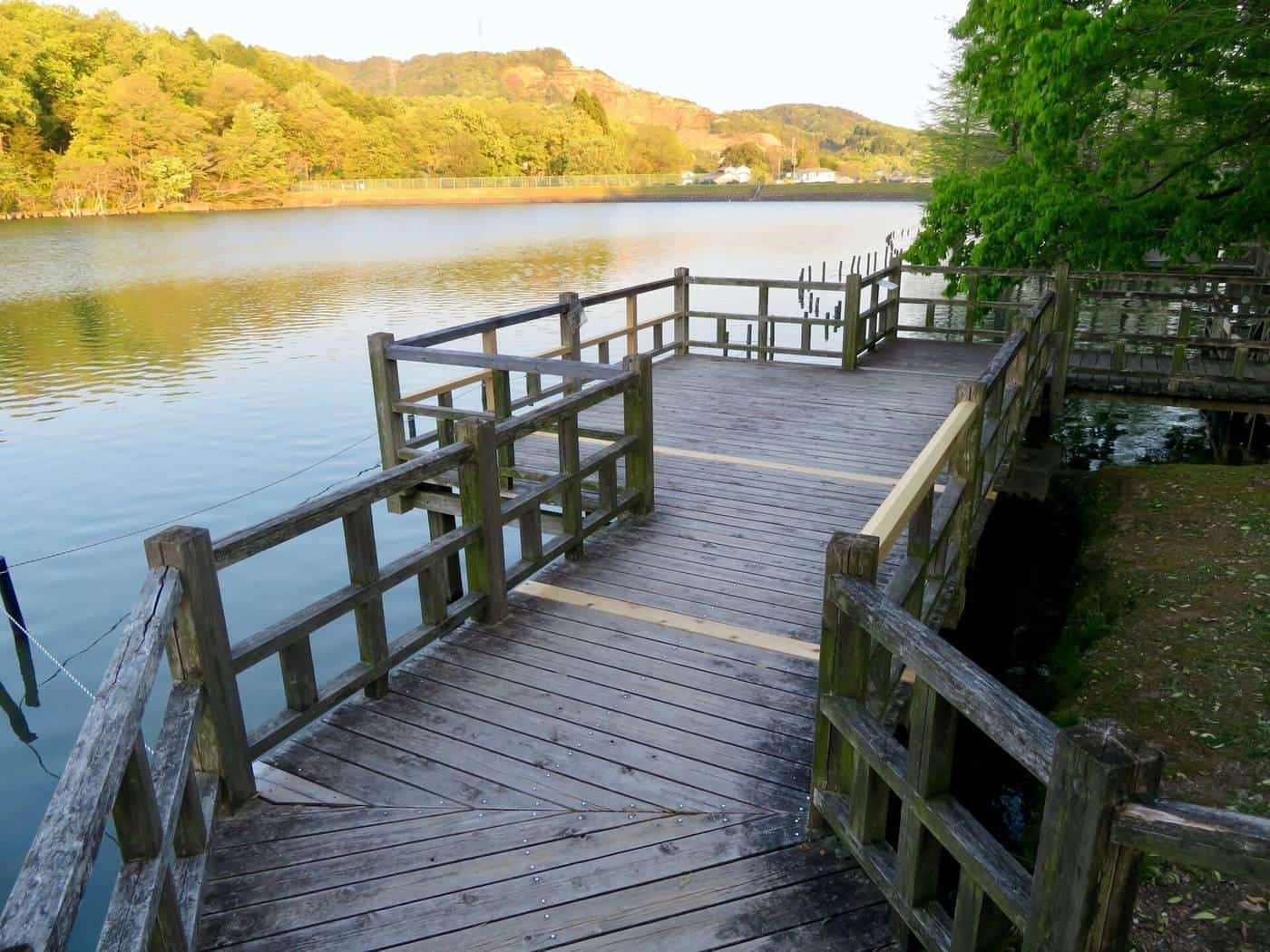 A timber boardwalk with railings beside a lake